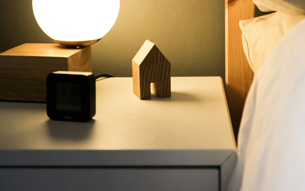 Table de nuit éclairée par une lampe douce, à côté d'un lit
