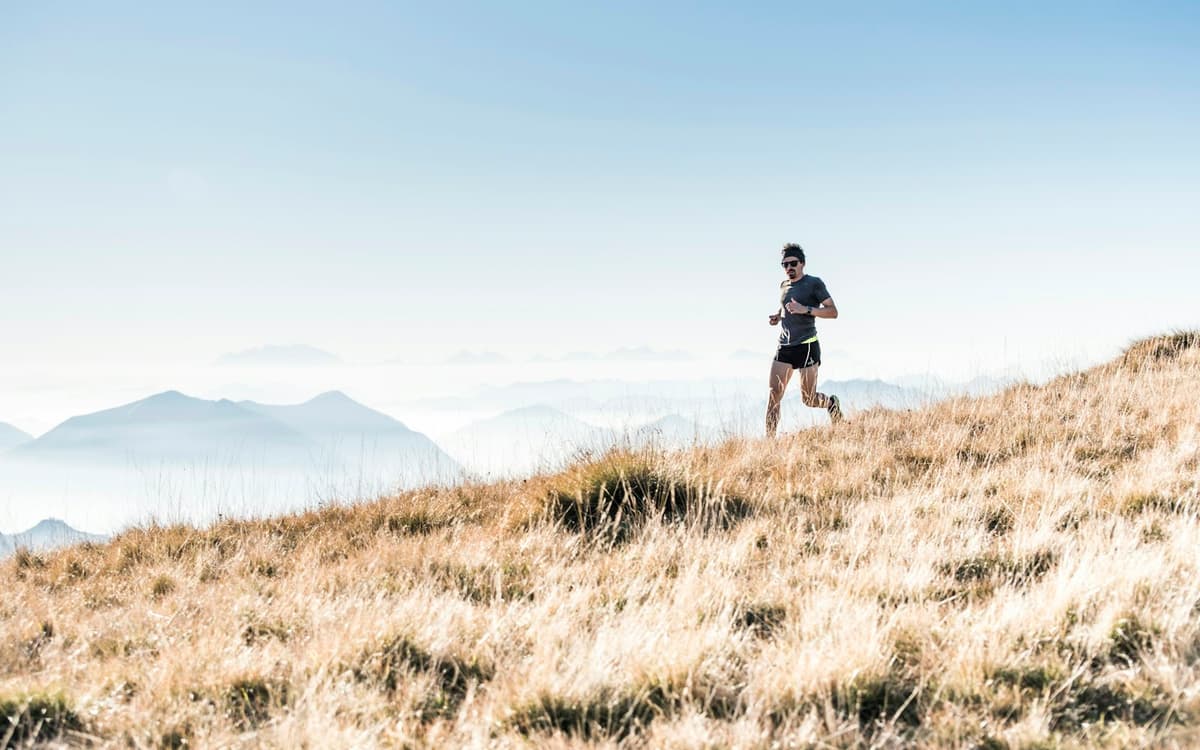 Coureur sur un sentier de montagne au-dessus des nuages