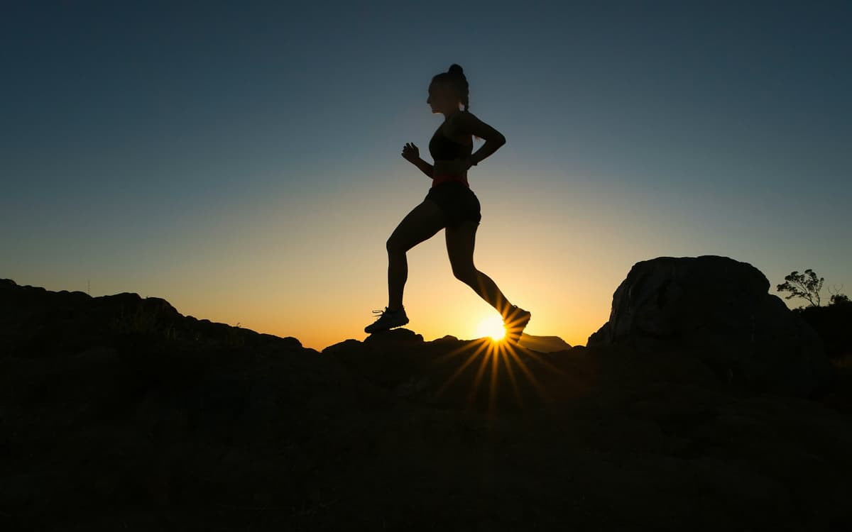 Silhouette d'une coureuse au lever du soleil